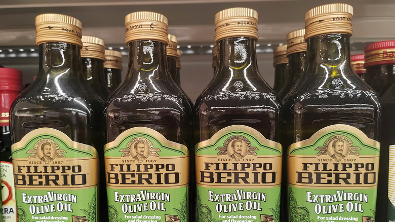 four bottles of filippo berio olive oil on the shelf at the grocery store