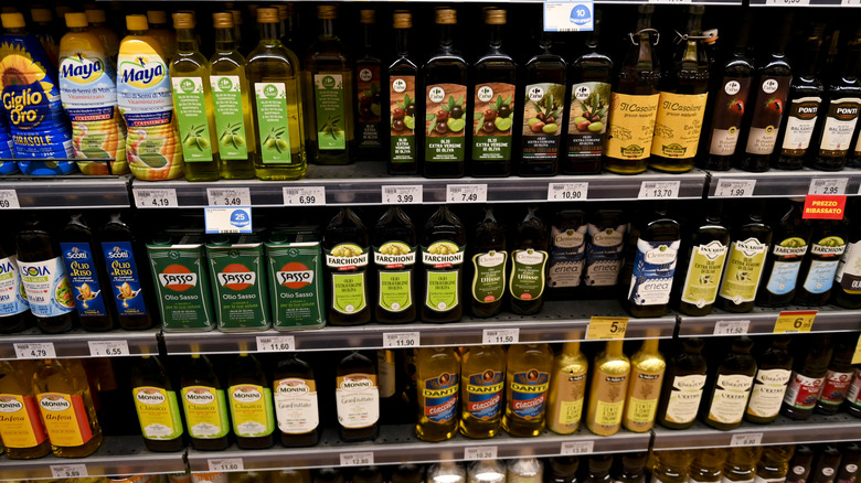 a display of numerous different olive oil bottles from different brands on grocery store shelves