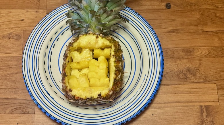 Heart shaped slices of pineapple in a hollowed out pineapple on a blue and white plate