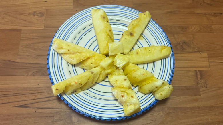 Long sticks of pineapple on a blue and white plate