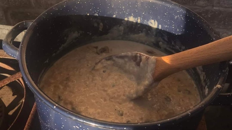 Spotted Pup rice pudding being cooked in a blue pot and stirred with a wooden fork