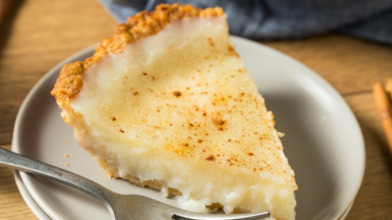 Slice of sugar cream pie sprinkled with cinnamon on a white plate