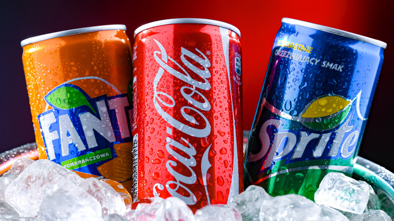 Cans of Fanta, Coca-Cola, and Sprite on ice.