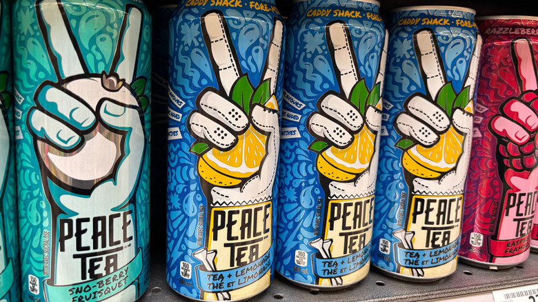 Cans of three different flavors of Peace Tea lined up on a store shelf