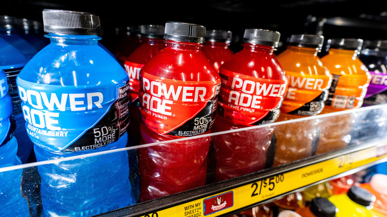 Blue, red, and orange Powerade bottles stocked on a store shelf
