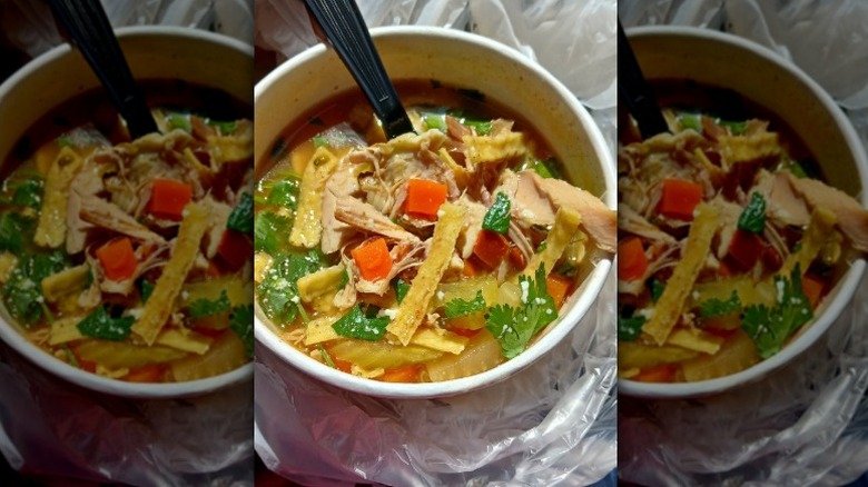 A to-go bowl of the Chicken Tortilla Soup from El Pollo Loco with a spoon sticking out of it.