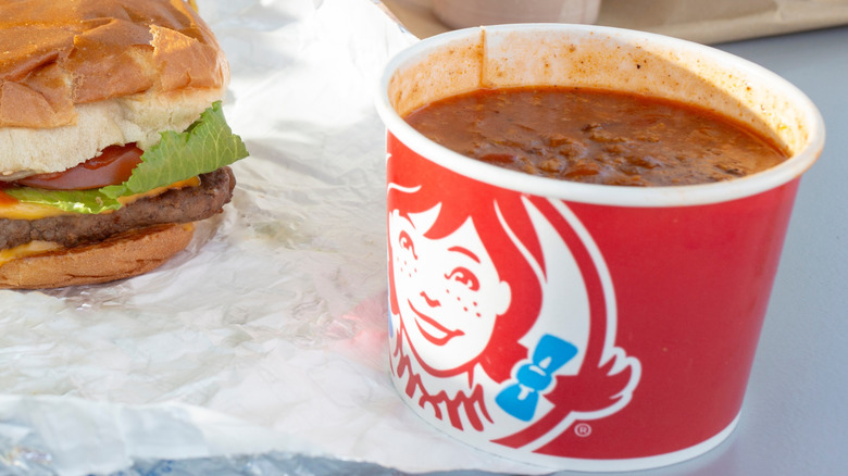 A bowl of Wendy's chili next to a burger.
