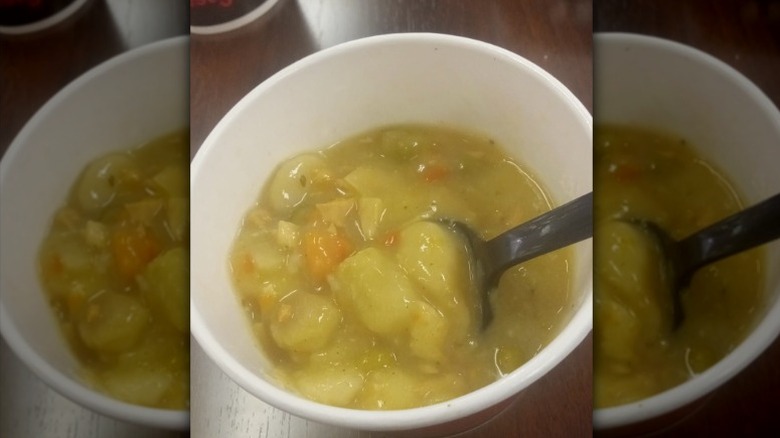 A spoon inside of a to-go bowl of Firehouse Subs Chicken and Dumpling Soup.