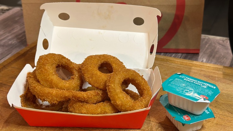 A box of Jack in the Box onion rings next to two packets of ranch