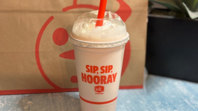 A Jack in the Box Strawberry Shake in plastic glass with lid and red straw