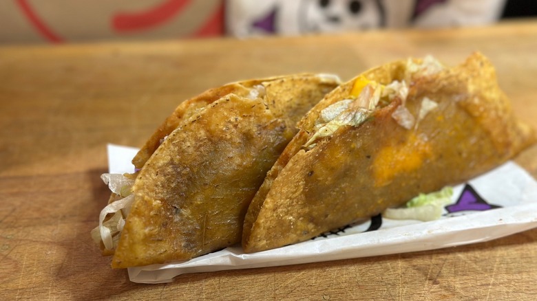 Two Jack in the Box Monster Tacos on white paper bag on table