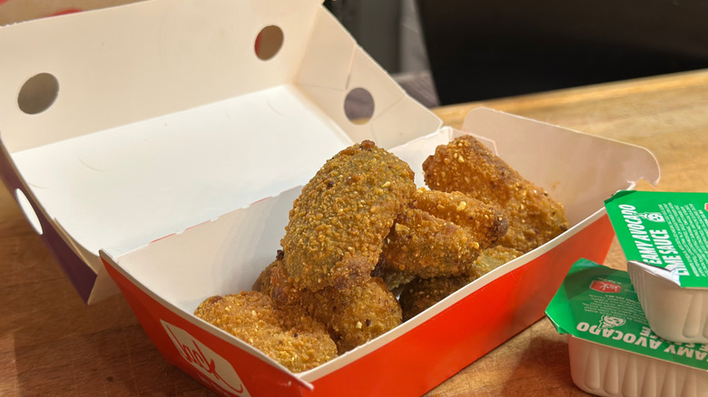 A box of six Jack in the Box jalapeno poppers next to packets of avocado lime sauce