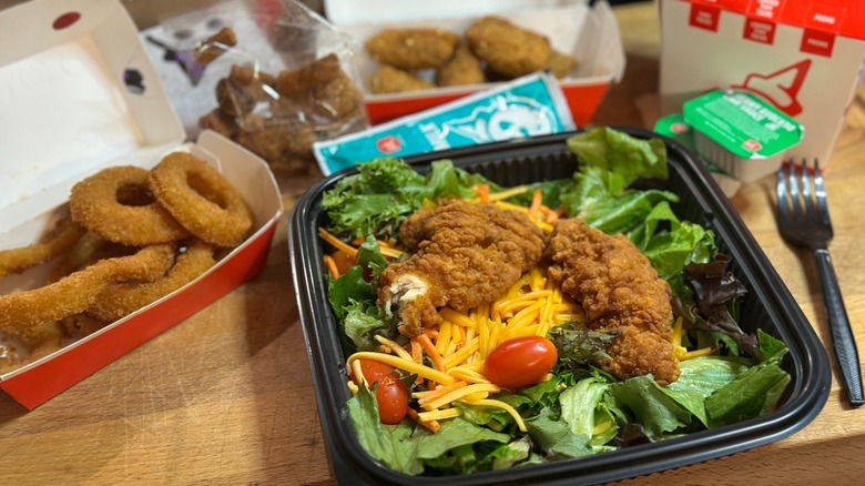 A sampling of Jack in the Box food items including onion rings and fried chicken salad