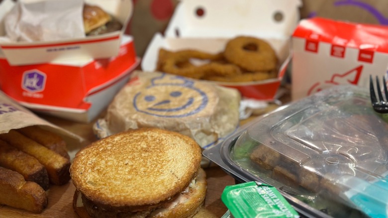 A spread of Jack in the Box menu items including sourdough sandwich, french toast sticks, and onion rings