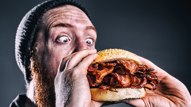 photo of a burly red-haired, bearded man about to devour a sandwich made purely of fried bacon