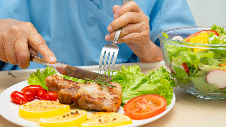 woman patient eating pork chop steak and vegetable salad
