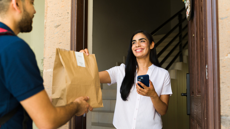 Woman receiving a food delivery in a brown paper bag