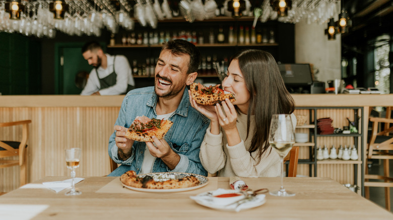 A happy couple share a pizza at a restaurant