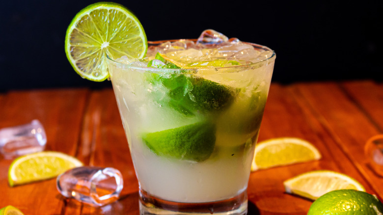 A close up of a caipirinha Brazilian cocktail, with a cut of lime on the side of the glass.