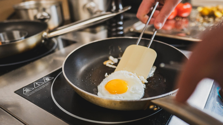 Scraping a fried egg off the surface of a non-stick pan