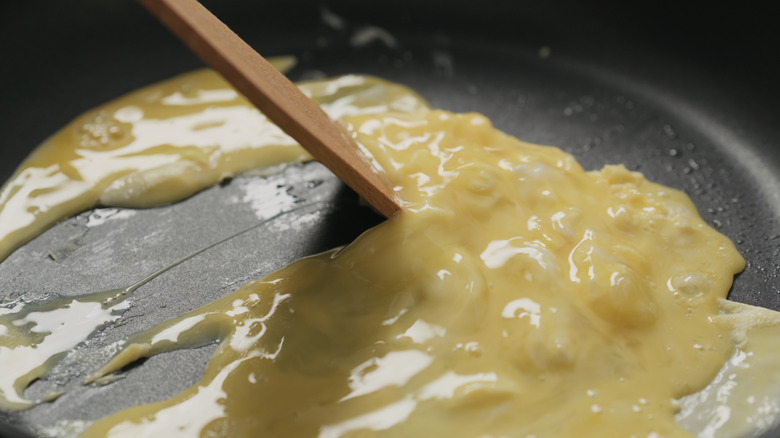 Making scrambled eggs on non-stick pan with wooden spatula