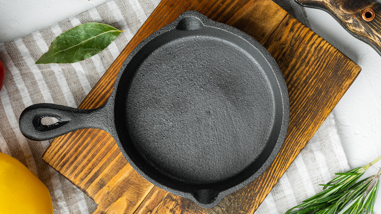 Empty cast iron pan on wooden cutting board