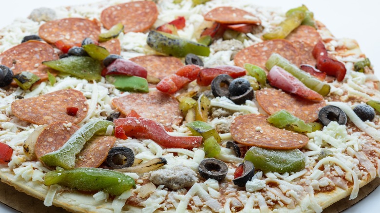 Close-up of a frozen pizza with cheese, pepperoni, olives, and bell peppers
