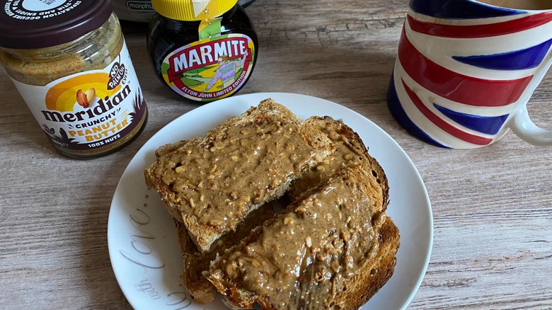 Marmite and Peanut Butter toast sandwich with jar of Marmite and peanut butter in background and coffee mug with British flag on it
