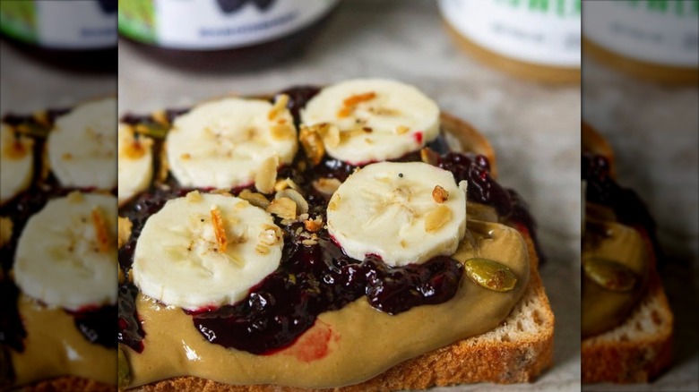 Elevated Peanut butter and jelly sandwich made with Marionberry Jam, nut butter, sliced banana , a sprinkle of granola on fresh slice of breads