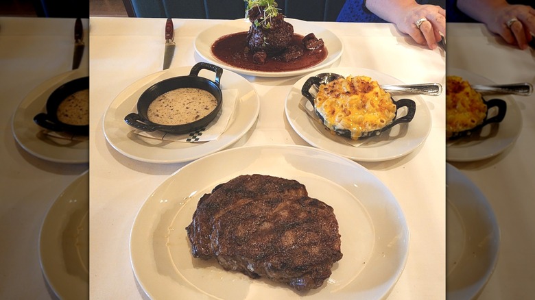 A restaurant table with plates of steak and macaroni.