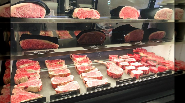 High-quality dry-aged steaks on display in a glass container.