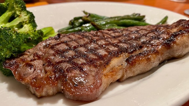 New york strip with broccoli and green beans on plate from Black Angus Steakhouse