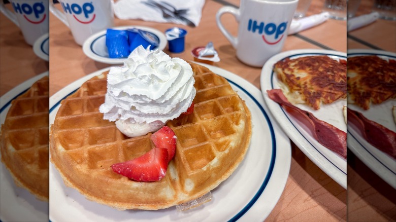 Waffle topped with sliced strawberries and whipped cream at IHOP