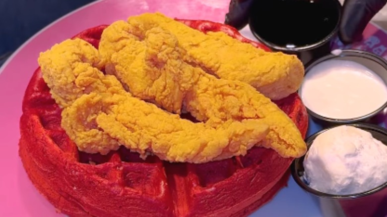Three fried chicken tenders on red velvet waffle at Serendipity 3