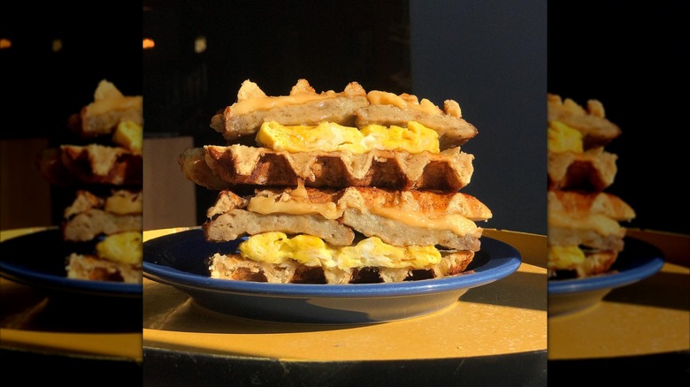 Two halves of waffle sausage gouda sandwich stacked on plate