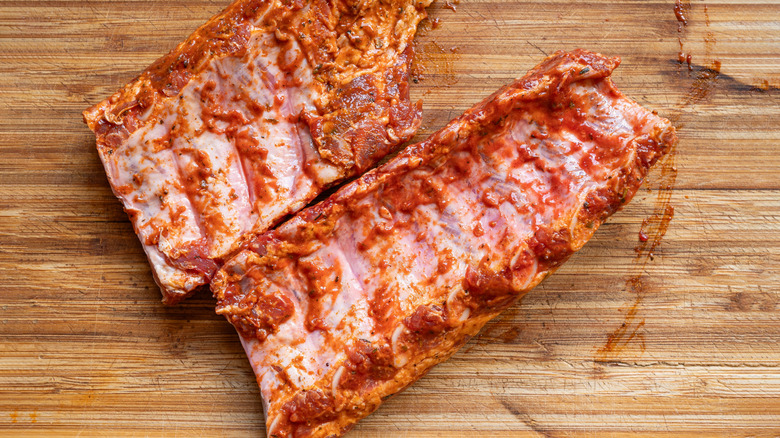 Two racks or raw pork ribs covered in a marinade