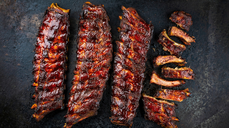 Racks of grilled ribs, one of which is sliced
