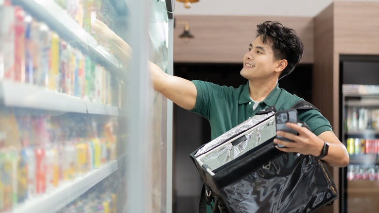 Grocery delivery service shopper with insulated delivery bag buying items for customers at supermarket
