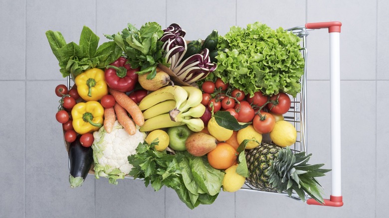 Supermarket shopping cart full of fresh vegetables and fruits