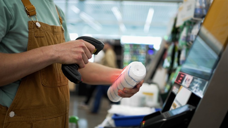 Buyer scanning various items at a self-checkout kiosk