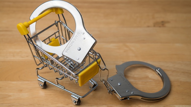 Handcuffs locked onto a miniature shopping cart on wooden table