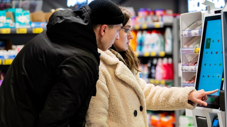 Young couple having issues scanning groceries at self-checkout in supermarket