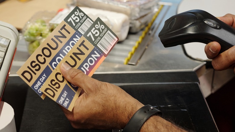 Closeup of arm scanning discount coupons at supermarket checkout line