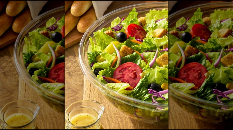 Olive Garden jumbo house salad with sauce and breadsticks on the side, mirrored