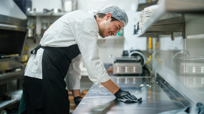 A chef cleaning a kitchen counter