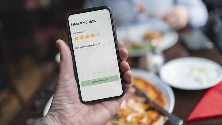 Person holding smart phone with restaurant rating app