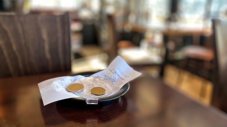 Restaurant bill with coins on a table