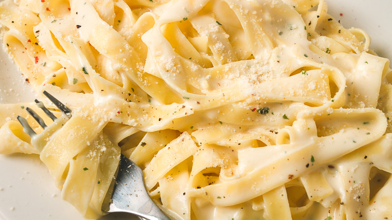 fettucine Alfredo on a plate with a fork twisting the noodles