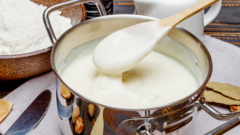 Béchamel in stainless steel pot with wooden spoon
