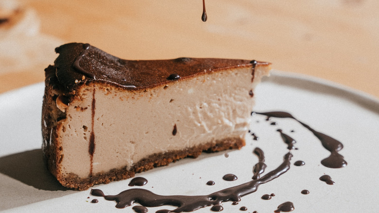 cheesecake on white plate with chocolate sauce drizzle
